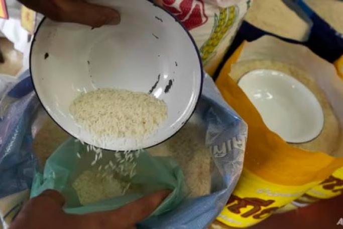 File photo of a worker scooping rice into a bag on Aug 10, 2023. (Photo: AP Photo/Sakchai Lalit)