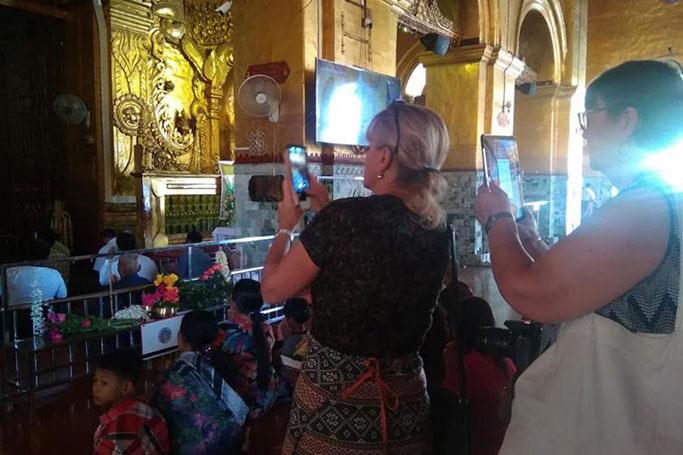 မဟာမုနိ ဘုရားကြီးကို ဖုန်းကင်မရာဖြင့် မှတ်တမ်းတင်နေသည့် ကမ္ဘာလှည့်ခရီးသွားများ (ခင်နှင်းဝေ/Myanmar Now) 