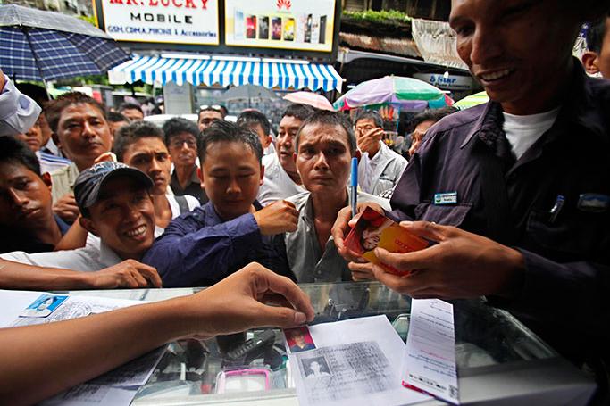 Myanmar man buys Ooredoo mobile sim card as other wait outside a mobile shop to buy, Yangon, Myanmar, 31 July 2014 Photo-LYNN BO BO