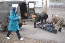 A woman walks as Ukrainian servicemen prepare to pick up a body in the north of Kyiv. File/AFP